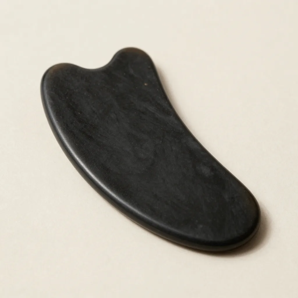 A long curved obsidian facial gua sha tool